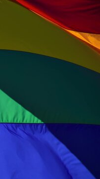 Slow motion gay pride flag blowing in the wind. Vertical Video.