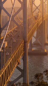 Traffic driving across the Bay Bridge towards downtown San Francisco at sunset. Vertical Video.