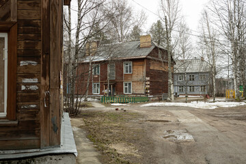 Row of old residential houses in provincial Far North of Russia during spring with melting snow and mud. © PuzzleSoul