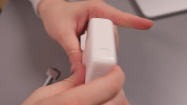 Unboxing charger details. Examining new electronic device closely. Closeup of hands revealing charger components. Detailed view of hands unpacking and examining electronic charger