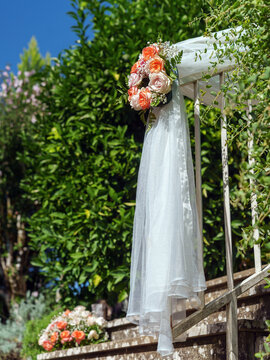 Decorazione nuziale elegante con velo bianco e bouquet di rose in giardino