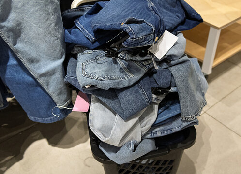 Pile of denim jeans and casual clothing arranged in a retail store. Fashion merchandise, clothing selection, shopping and apparel retail concept.