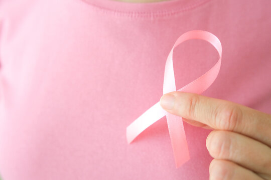 Breast cancer awareness background. Woman holding pink silk ribbon in hands