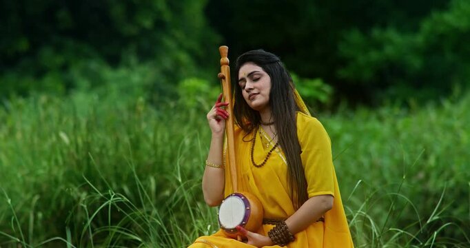 Saint Mirabai immersed in Krishna devotion, sitting in lush green nature during the monsoon, playing a traditional ektari with prayer beads