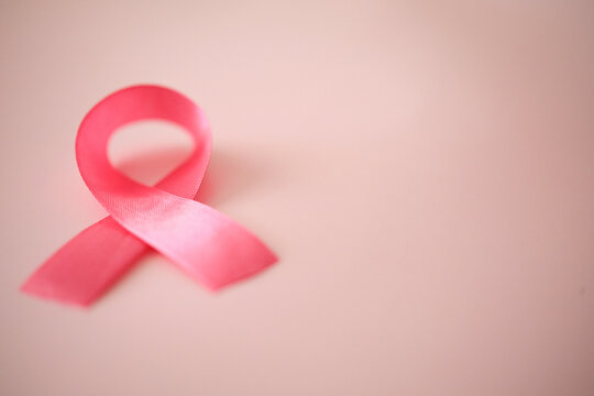 Pink satin silk ribbon on pale pink background. Breast cancer awareness symbol