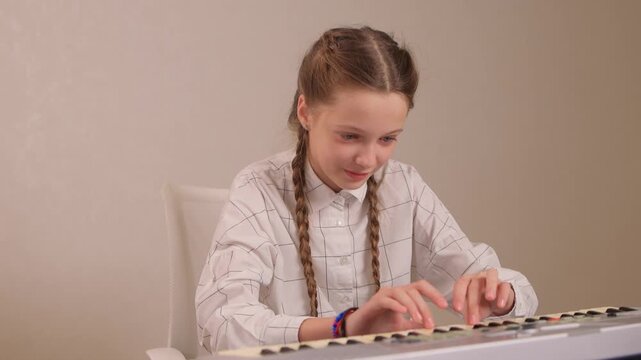 Young female musician rehearsing melodies on digital piano at home. Brightly lit scene of youthful girl honing musical skills on electronic keyboard in cozy environment