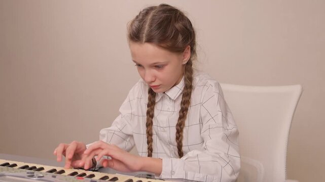 Young female musician rehearsing melodies on digital piano at home. Brightly lit scene of youthful girl honing musical skills on electronic keyboard in cozy environment
