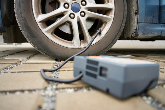 Portable tire inflator connected to car wheel on driveway
