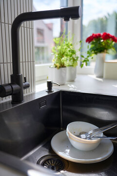 Used bowl, plate and cutlery with food residue are left in kitchen sink