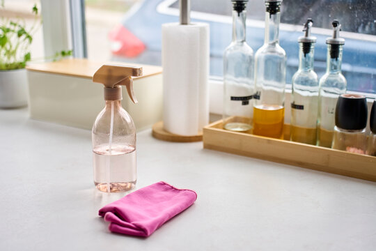 Spray bottle and pink cleaning cloth placed on kitchen countertop