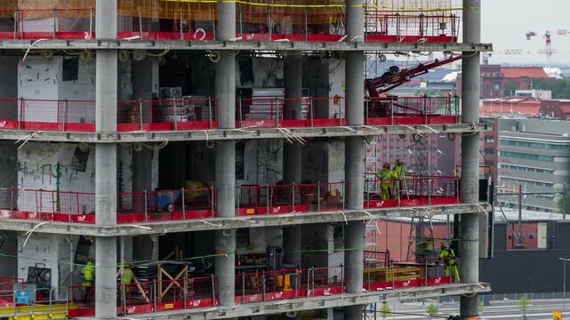 Helsinki, Uusimaa, Finland - 26 August 2022: View of construction workers on the scaffolding of the Kalasatama high rise building project. Timelapse.