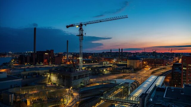 Helsinki, Finland - 24 April 2022: View of the Kalasatama high rise construction site with a tower crane against a sunset sky. Timelapse.