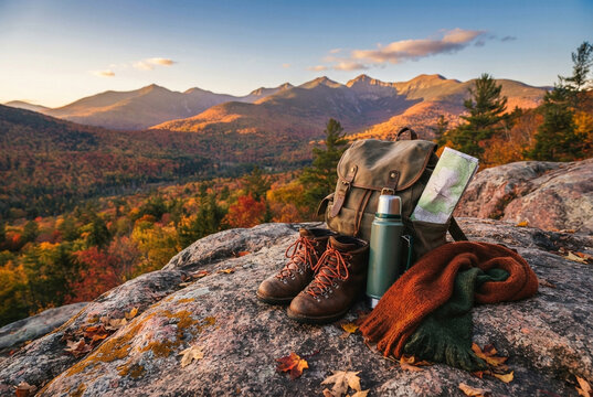 Hiking boots, backpack, and thermos resting on rocky mountain cliff.