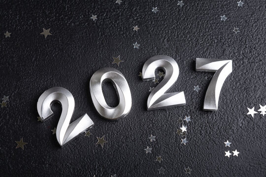 New Year 2027 celebration numbers with small silver stars on dark background