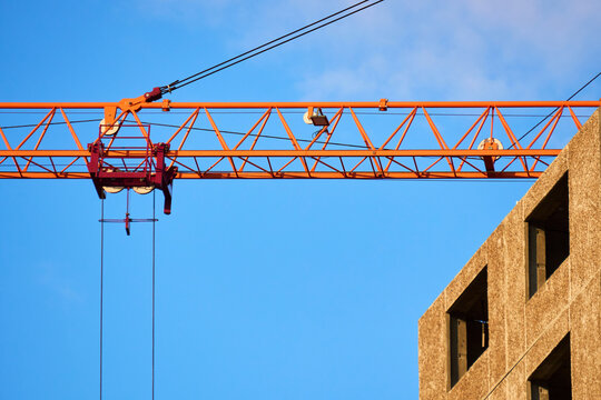 Orange tower crane jib with trolley and pulleys in action