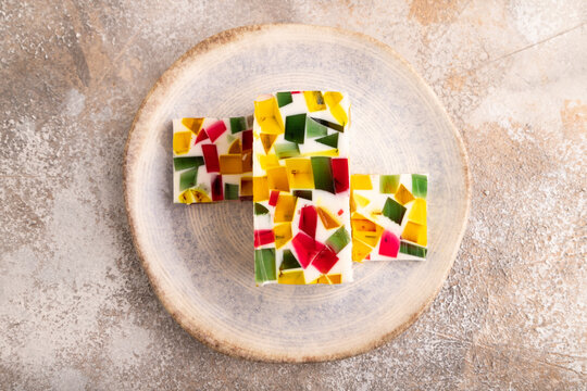 Colored Fruit and milk jelly on brown concrete, top view, close up
