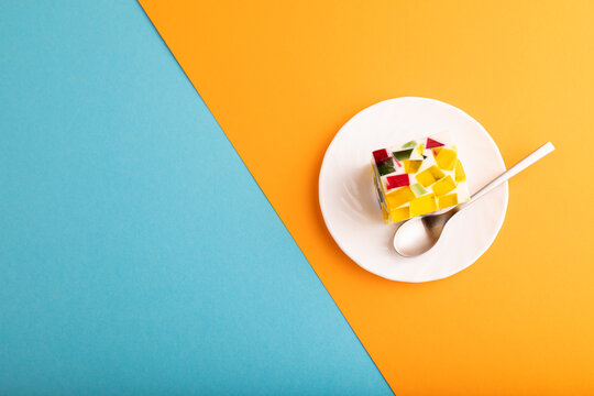 Colored Fruit and milk jelly on blue and orange paper, top view, copy space