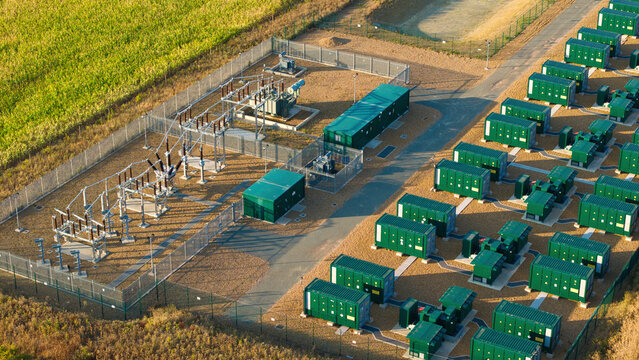 Aerial view of the Battery Energy Storage System at BESS Grendon with rows of green battery containers, electrical transformers, and security fencing in Northampton, England, United Kingdom.