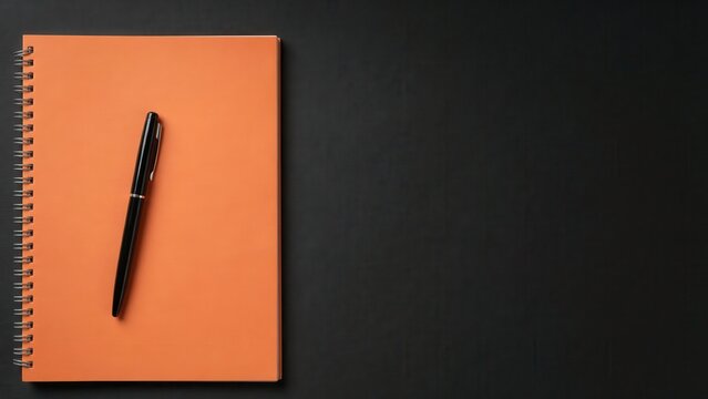 A black pen resting on an orange spiral notebook against a dark background. This composition is perfect for business planning and creative writing concepts.