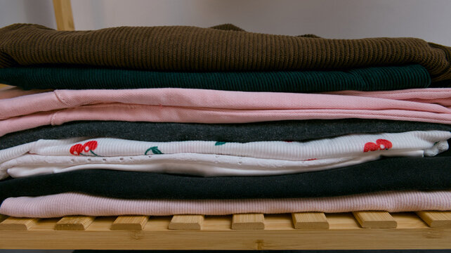 Neatly folded clothes stack on wooden shelf