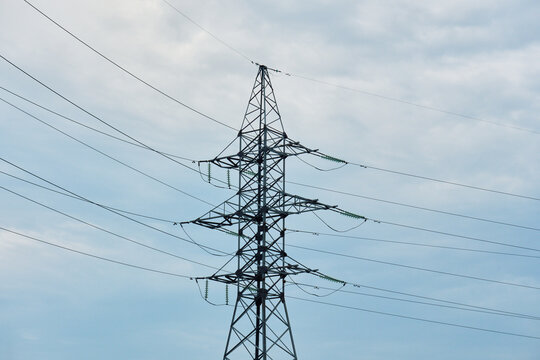 Steel lattice power transmission pylon with glass insulator strings and high voltage wires isolated against blue sky