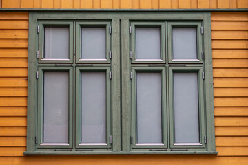 Fototapeta premium Double window with green frames in yellow wooden building wall