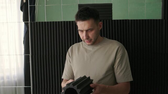 Soundproofing test on acoustic board. Evaluating sound insulation with acoustic panel testing. Technician assesses soundproofing effectiveness of acoustic panels in studio