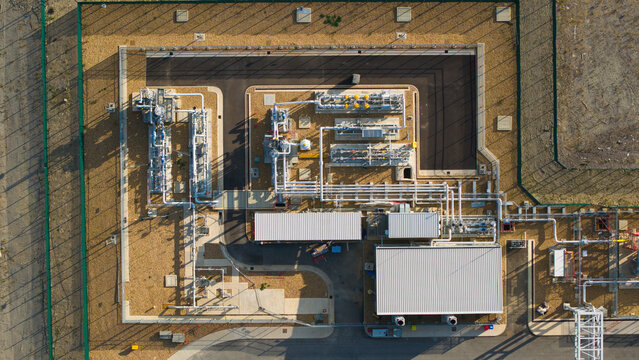 Aerial view of the Millbrook Power Plant featuring industrial piping, storage tanks, and facility buildings within a fenced perimeter in Stewartby, England, United Kingdom.