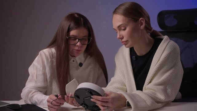 Female designers collaborating on electronic prototypes with soft lighting. Women focused on developing and testing new electronic mockups amid collaborative discussion