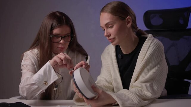 Female designers collaborating on electronic prototypes with soft lighting. Women focused on developing and testing new electronic mockups amid collaborative discussion