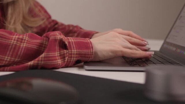 Young lady editing content from home. Female professional concentrating on digital editing task. Young woman in casual attire diligently working on her laptop at home