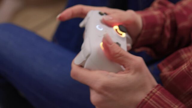 Happy woman gaming. Confident woman with braided hair enjoys gaming in cozy atmosphere. Woman smiling and concentrating while holding game controller in warm indoor environment