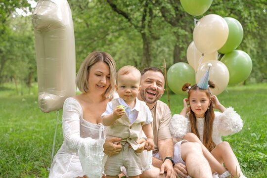 The young, happy family is celebrating their son&rsquo;s first birthday outdoors in the park.