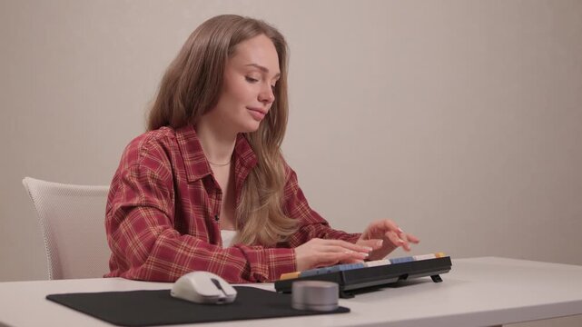 Focused woman typing on keyboard. Woman engaged in remote writing tasks. Female professional diligently performing editing and writing activities with organized workspace