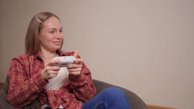 Happy woman gaming. Confident woman with braided hair enjoys gaming in cozy atmosphere. Woman smiling and concentrating while holding game controller in warm indoor environment