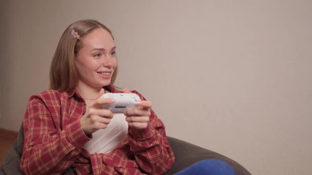 Happy woman gaming. Confident woman with braided hair enjoys gaming in cozy atmosphere. Woman smiling and concentrating while holding game controller in warm indoor environment