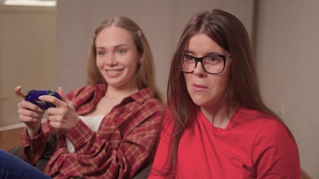 Women play games. Relaxed friends enjoying video games with cheerful interactions. Two women engage in friendly game night amid comfortable surroundings and joyful laughter