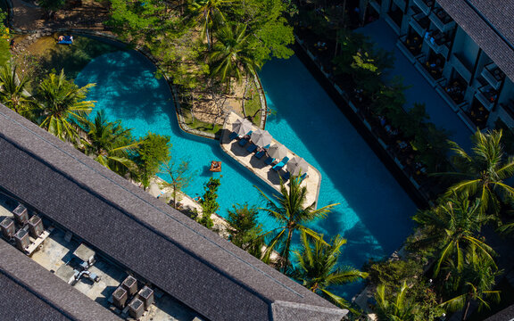 Aerial view of Marriott's Bali Nusa Dua Gardens featuring a turquoise swimming pool with lounge chairs on a small island, surrounded by palm trees in Kecamatan Kuta Selatan, Bali, Indonesia.
