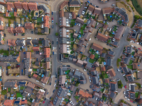 Aerial view of a modern residential housing estate with rows of houses, private gardens, and winding streets in Bedford, England, United Kingdom.