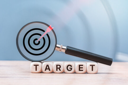 Magnifying glass with target icon resting on wooden letter cubes spelling TARGET word. Business goal setting, market research, strategic audience focus, SEO targeting and success planning concept.