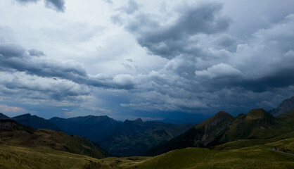Fototapeta premium serene mountain landscape under a cloudy sky, captured from a high vantage point in a rural setting with lush green grass and rugged rocks, travel and nature photography.