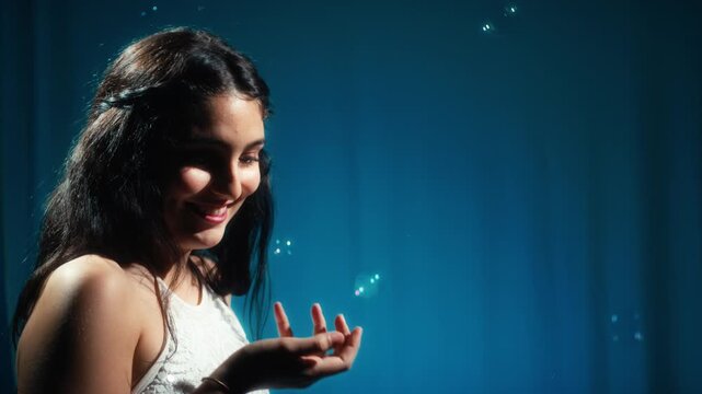 Young woman smiles in a dream environment while playing with soap bubbles