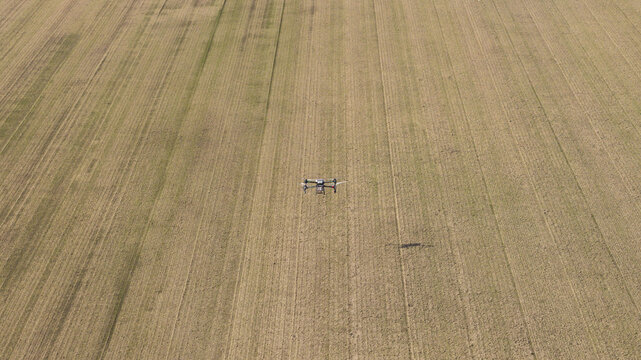 Aerial view of a drone flying over a vast, flat, harvested agricultural field with visible tractor tracks in Zeewolde, Flevoland, Netherlands.