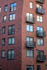 Obraz premium Modern brick apartment tower with balconies and dark windows.