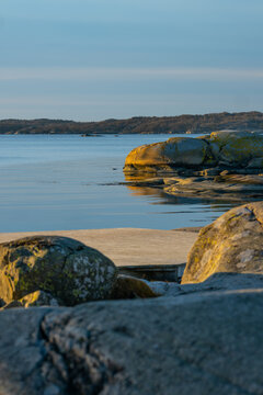 Rocky shoreline and wooden pier in peaceful bay.