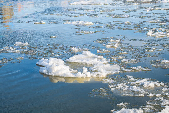 Frozen river surface with scattered ice chunks and reflections.