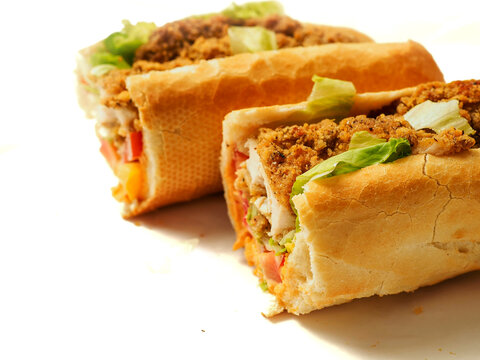Crispy fried chicken filling in a soft, golden-brown roll bun. Fresh lettuce peeking through the savory meat. Clean white background highlights food texture and color. Perfect for fast food