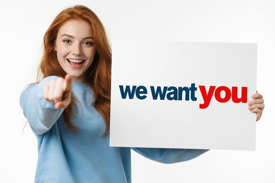 Young redhead woman points forward holding we want you sign. She seeks new hires for her business, invites to join team. Opportunity for employment, career growth.