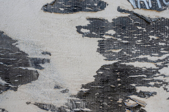 Urban street wall with old peeling posters and paint. White gray black colors