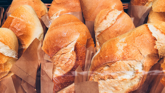 Fresh artisan bread loaves displayed in paper packaging at a bakery store. Concept of traditional baking, fresh food retail, carbs, and wholesome nutrition.